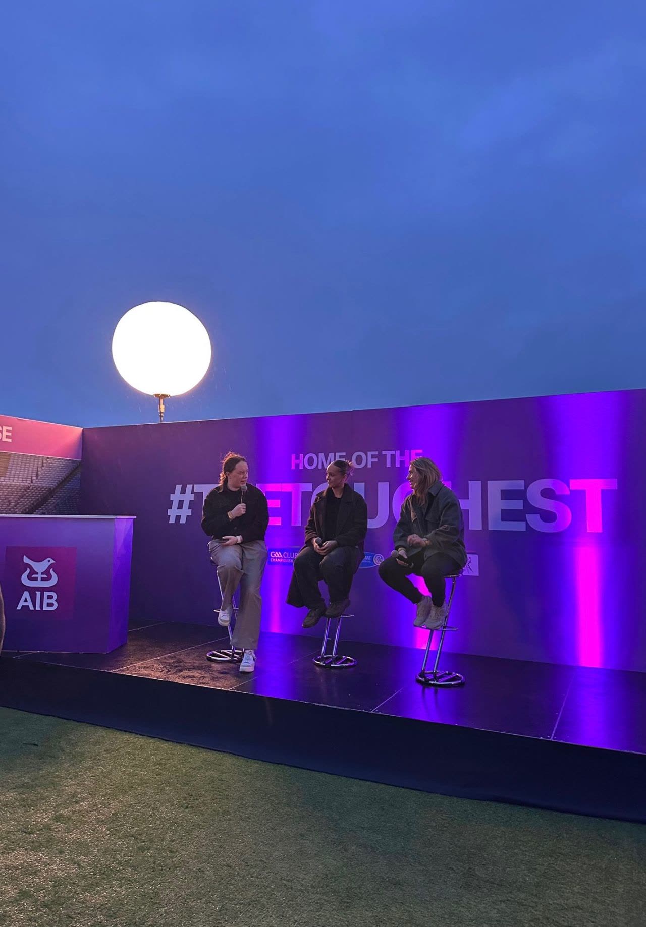 Orla Keeling on stage with a microphone, hosting a live panel under the lights