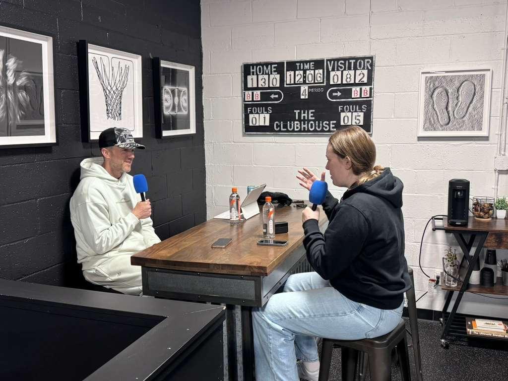 Orla recording a podcast interview across the table from her guest