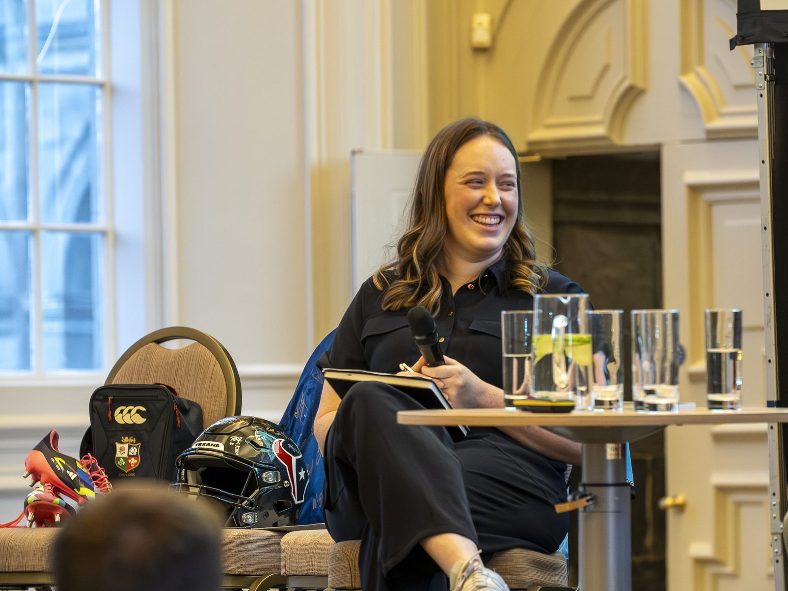 Orla Keeling laughing on stage, notebook in hand, hosting a live conversation